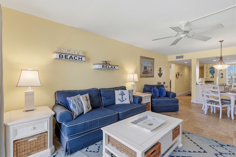 Living room with sofa, armchair, coffee table, and dining area beyond
