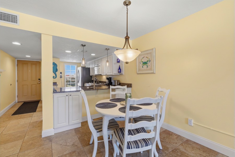 Dining table under a pendant light beside the kitchen breakfast bar