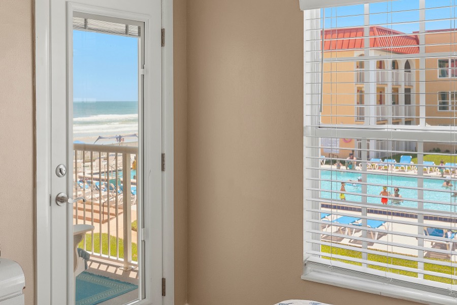 View of the beach, ocean, and pool deck from the primary bedroom