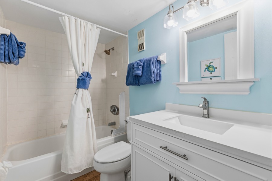 Light-blue bathroom with white vanity and tub-shower