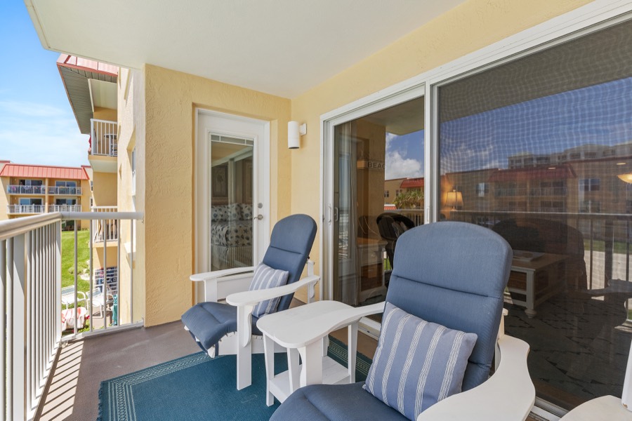 Balcony with two blue reclining chairs and a side table