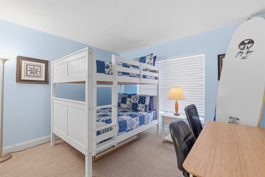 Guest room with white bunk beds, nautical bedding, and a decorative surfboard