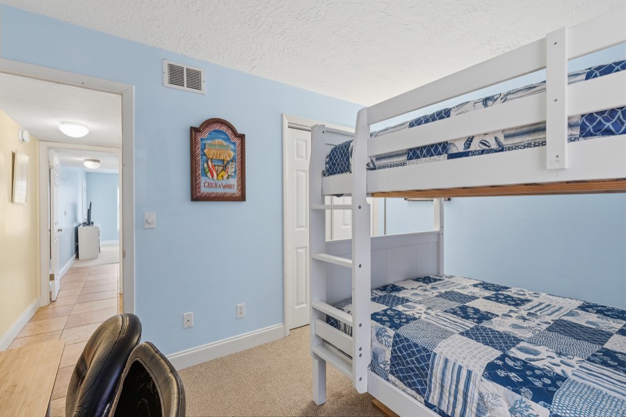 Bunk-bed guest room with patchwork blue bedding and ladder