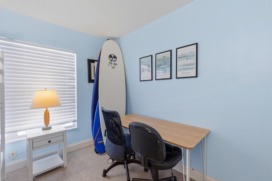 Desk corner of the guest room with surfboards and framed beach prints