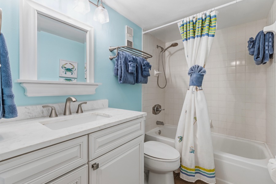 Second bathroom with white vanity and tropical shower curtain