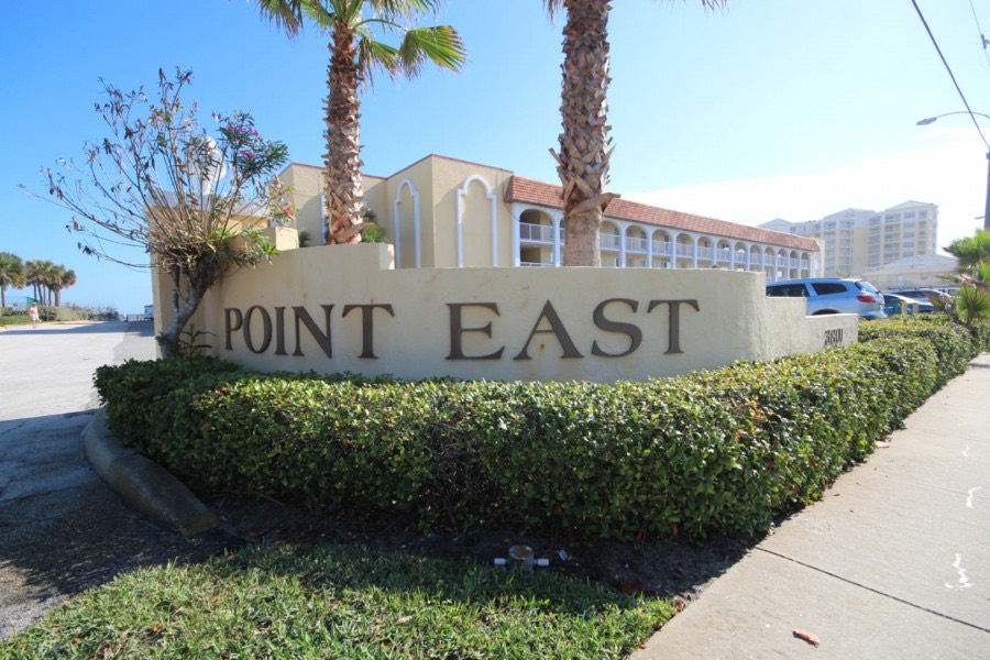 Point East community entrance sign flanked by palm trees
