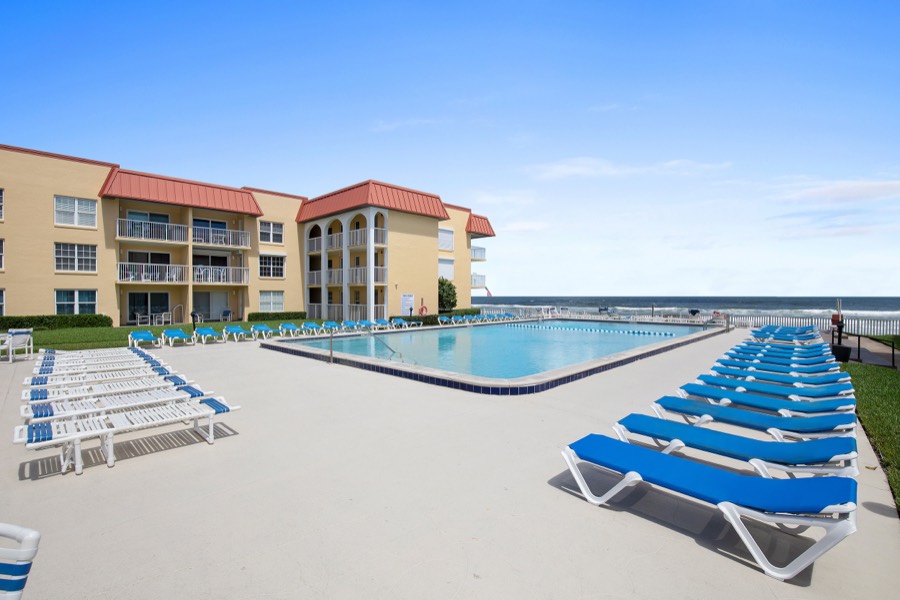 Oceanfront lap pool lined with blue and white loungers