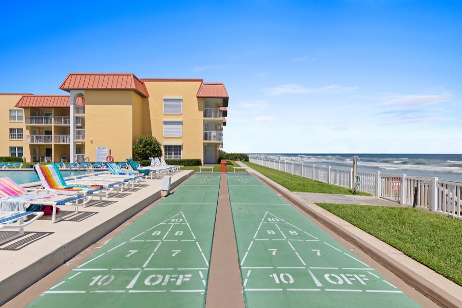 View down two green shuffleboard courts toward the ocean